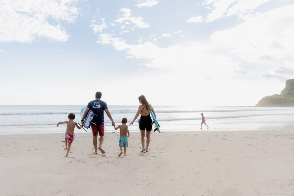 Family heading to the beach with surfboards at Rancho Santana, Nicaragua