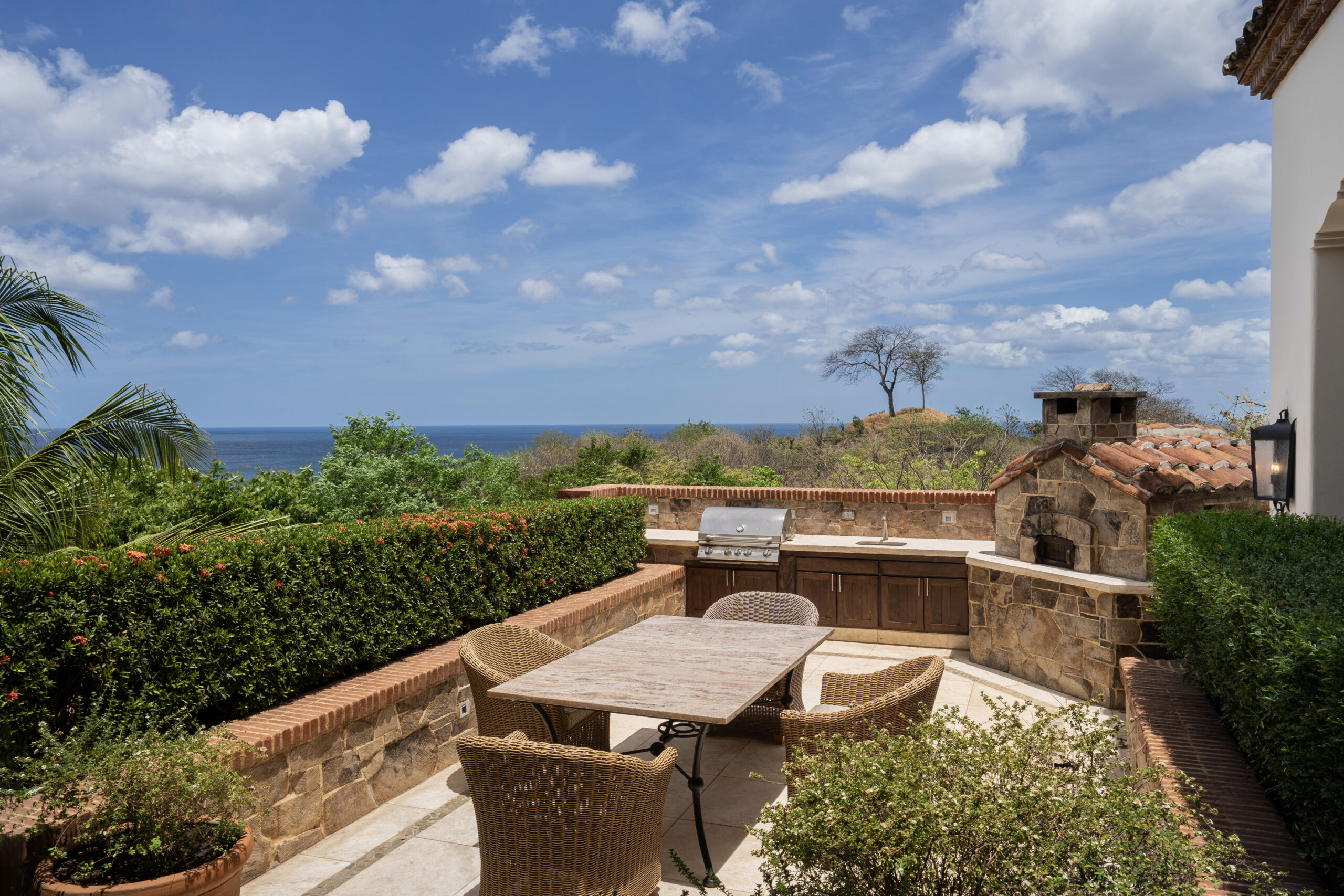 http://A%20sunny%20outdoor%20patio%20at%20Villa%20Escondida%20features%20a%20wooden%20table,%20wicker%20chairs,%20built-in%20grill,%20and%20stone%20counters,%20surrounded%20by%20greenery%20and%20overlooking%20the%20ocean%20under%20a%20blue%20sky—perfect%20for%20enjoying%20your%20co-owned%20luxury%20home.