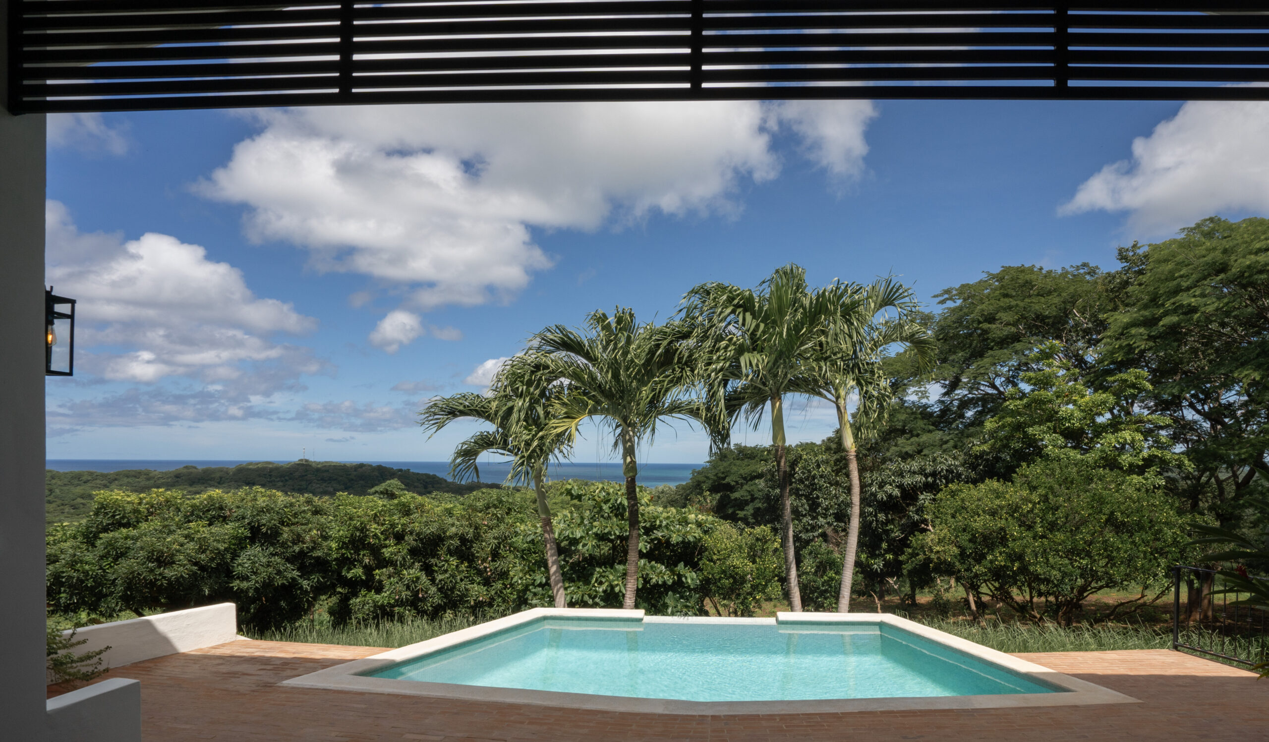 http://Enjoy%20a%20peaceful,%20tropical%20scene%20at%20Casa%20Reposo,%20where%20a%20private%20swimming%20pool%20is%20framed%20by%20three%20palm%20trees%20and%20overlooks%20lush%20greenery%20and%20glimpses%20of%20the%20ocean%20beneath%20a%20partly%20cloudy%20blue%20sky.